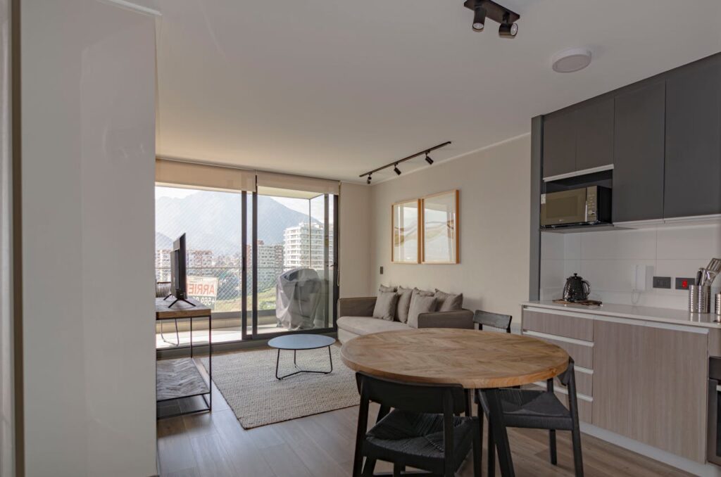 Spacious modern living room with kitchen area overlooking city balcony view.